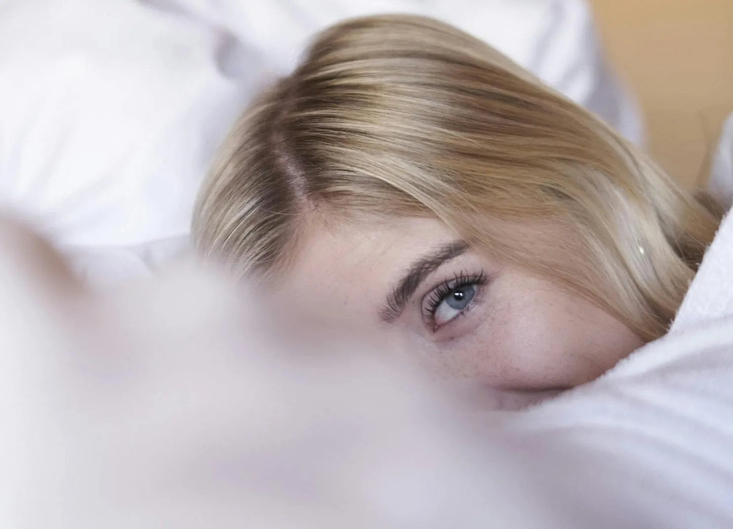 Close-up of a part of a face with blonde hair and a blue eye.