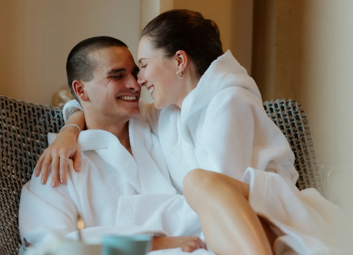 Couple in white robes sharing a joyful moment indoors