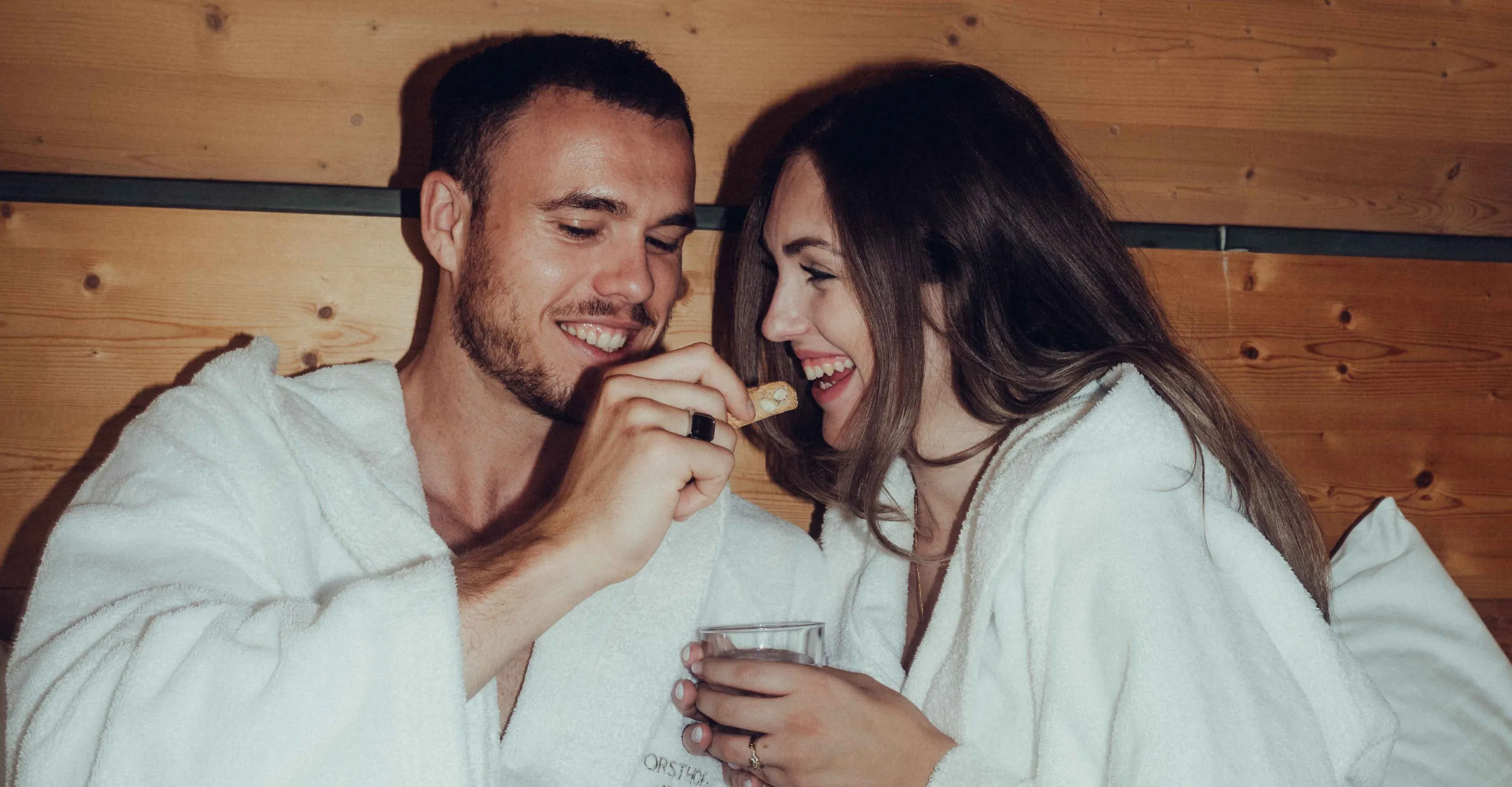 Couple in bathrobes with wooden paneling in background