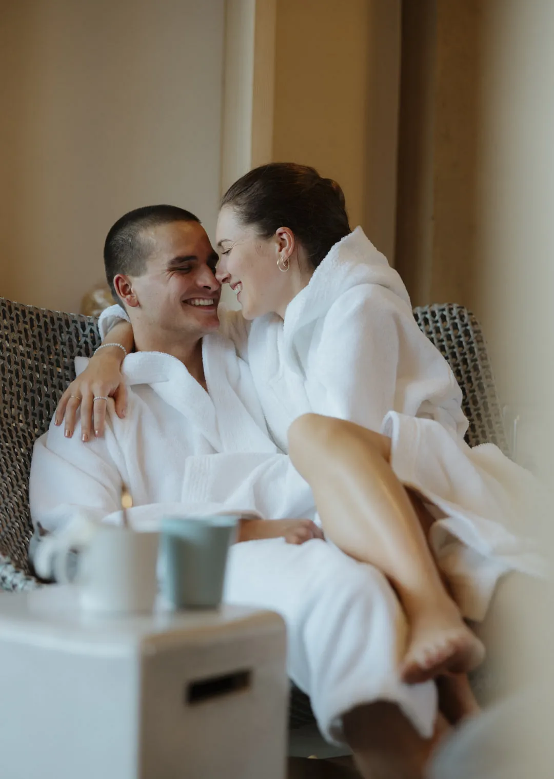 Couple in bathrobes, relaxed and happy in a hotel room.