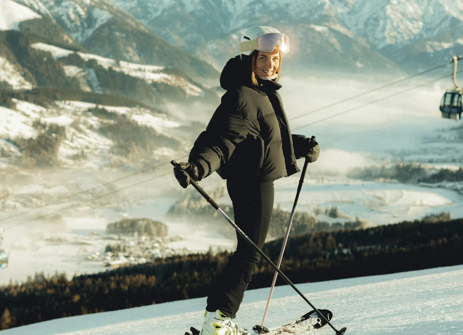 Skier on snowy slope with mountains and ski lift in the background