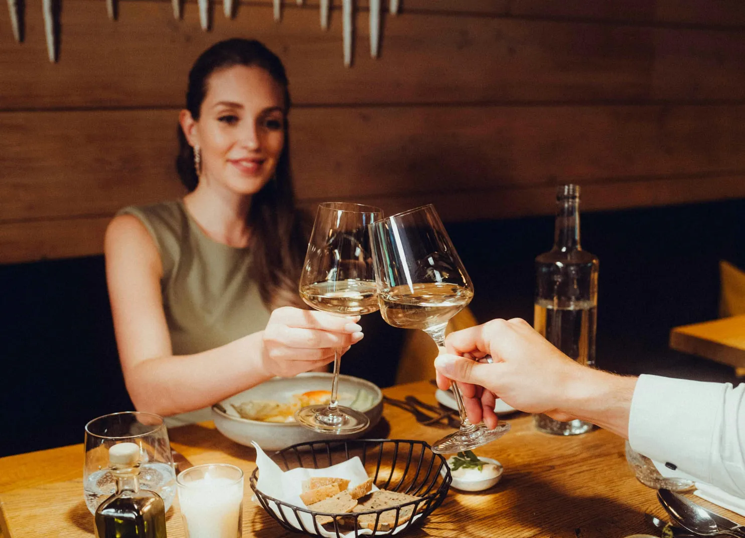 Frau toastet mit Weingläsern an einem Esstisch