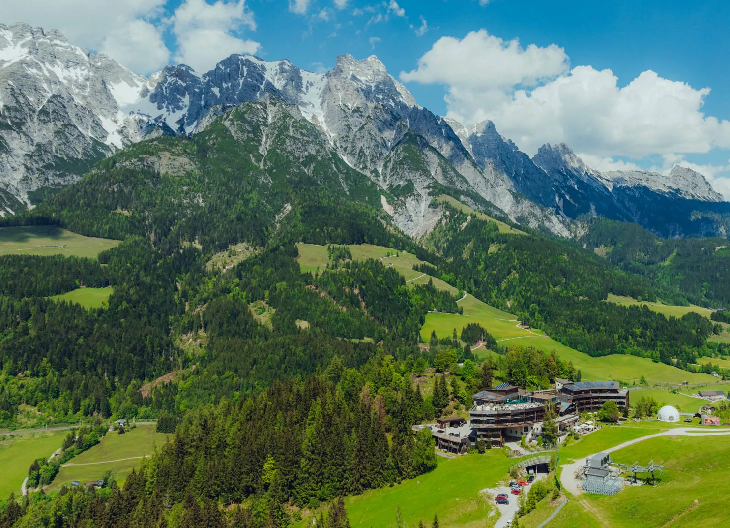 Aerial view of Holzhotel Forsthofalm in Leogang, surrounded by mountains and forests