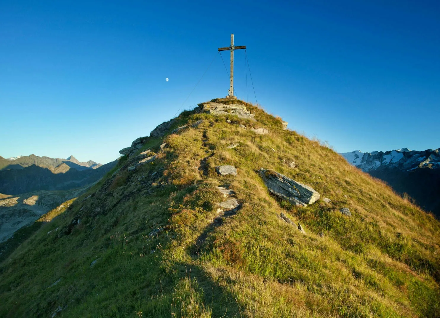 Mountain peak with a cross against a clear blue sky