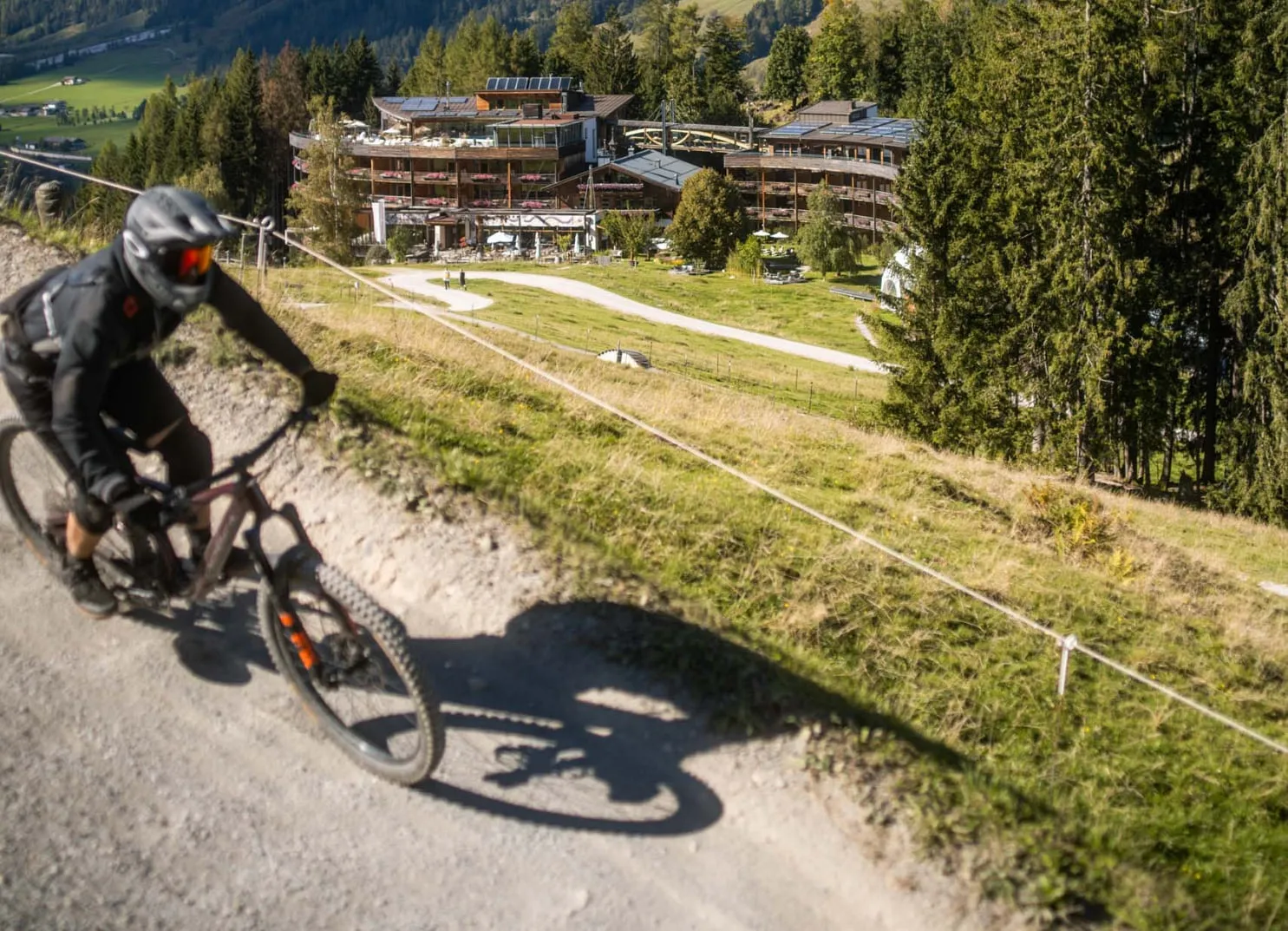 Mountainbiker fährt einen Trail mit einem Holzhotel im Hintergrund