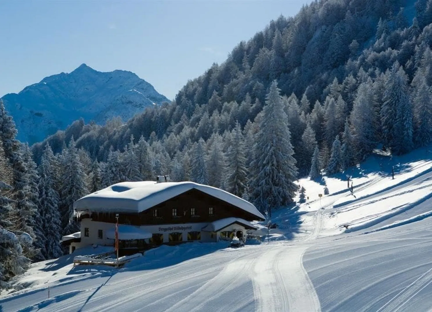 Schneebedecktes Haus in den Bergen mit Tannenwald im Hintergrund