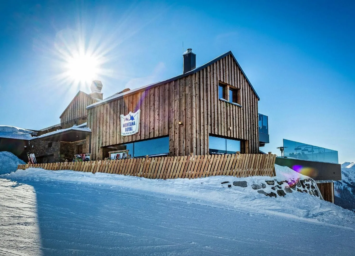 Holzgebäude auf schneebedecktem Berg mit strahlender Sonne