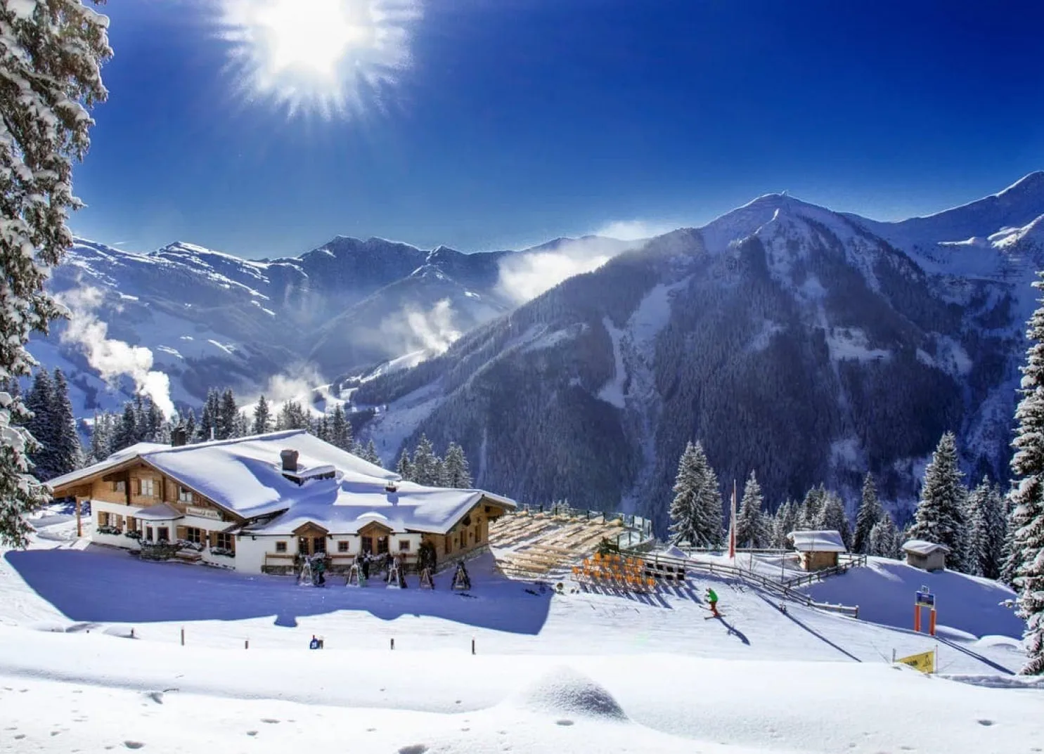 Schneebedeckter Berg mit Chalet und Pisten im Vordergrund