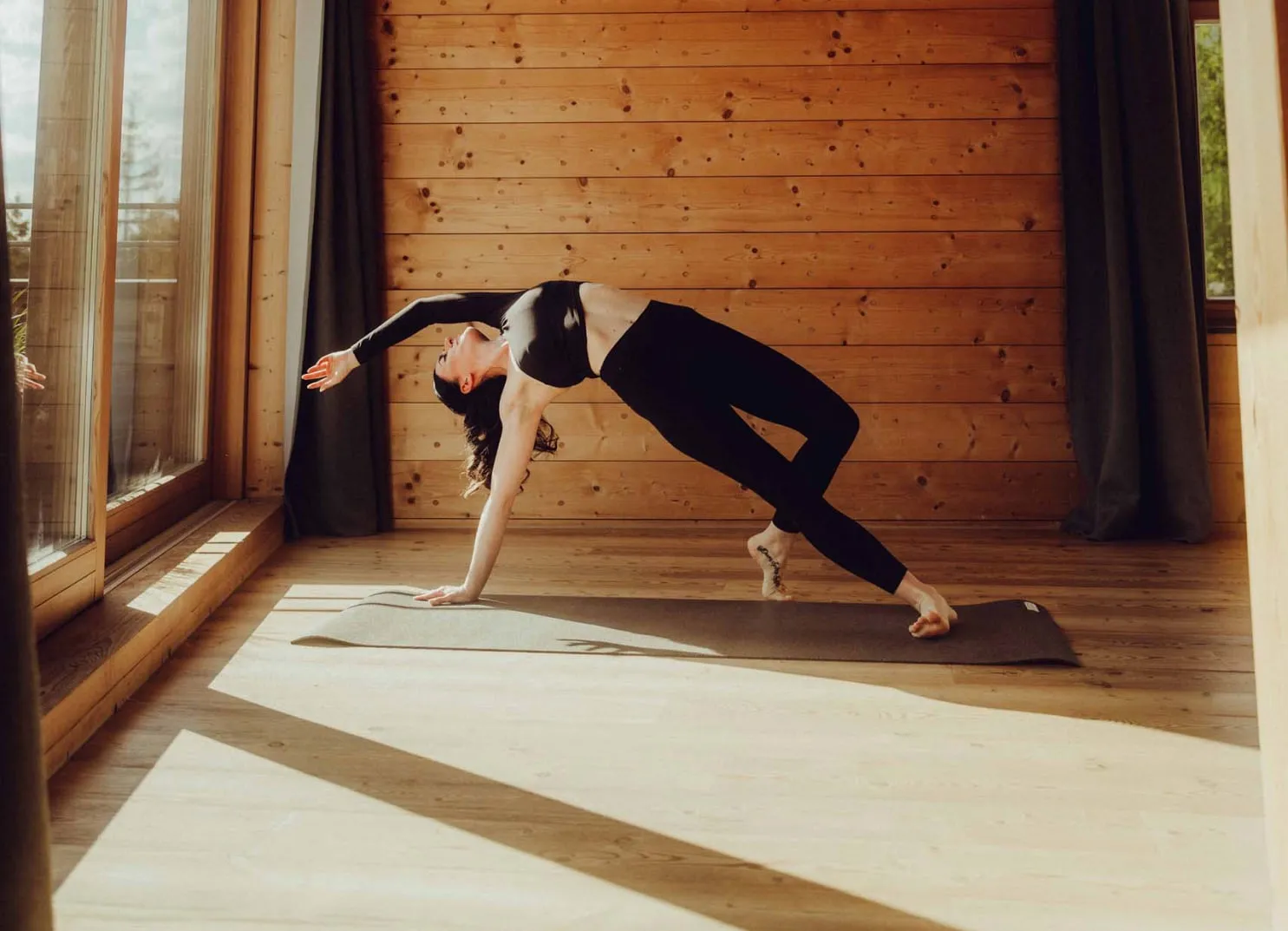 Frau praktiziert Yoga in einem Holzhotel mit Holzvertäfelung