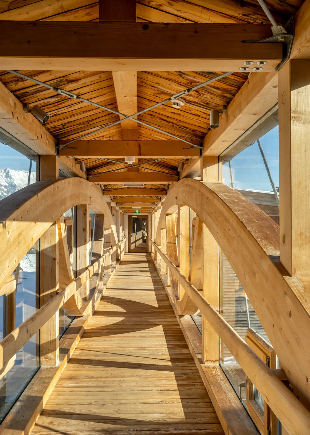 Holzbrücke mit Dach, seitlich verglast, in einem modernen Gebäude