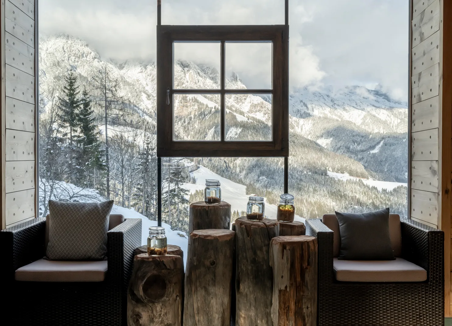 Gemütlicher Sitzbereich mit Blick auf schneebedeckte Berge durch ein Fenster