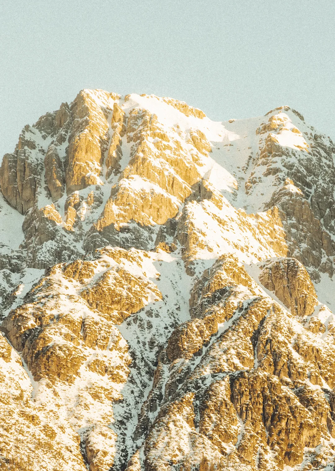 Schneebedeckte Berge mit goldenen Gesteinen im Licht.