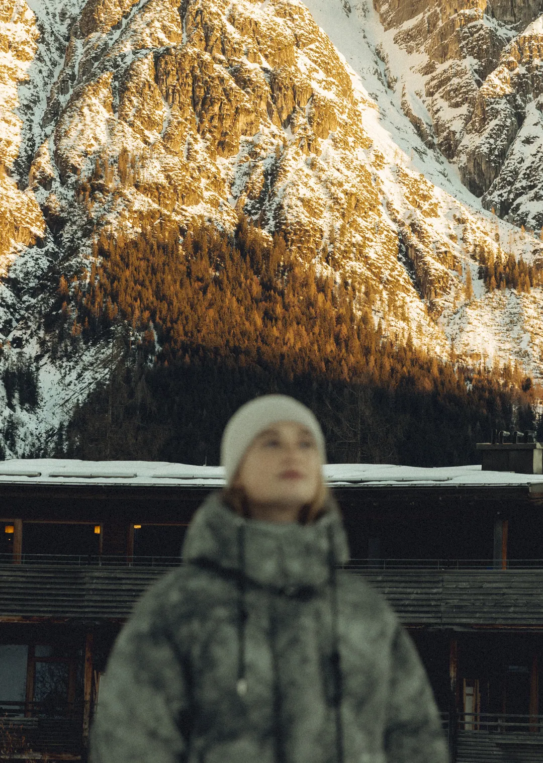 Person in warmer Kleidung vor schneebedeckten Bergen