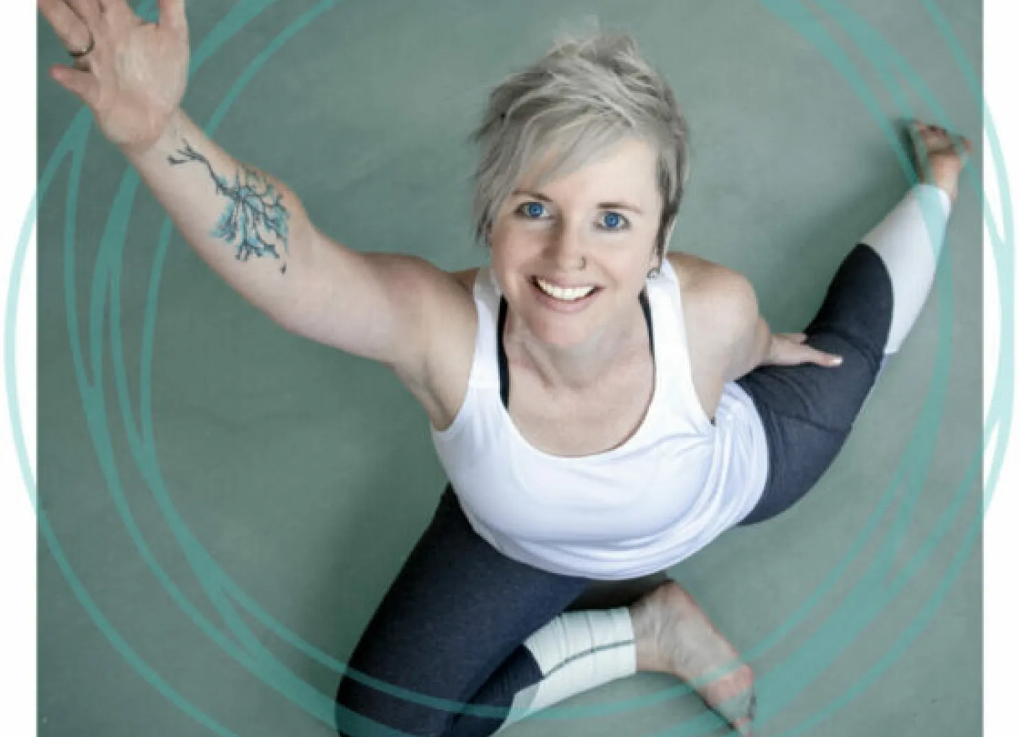 Lächenende Person dehnt sich auf einer grünen Fläche und zeigt ein Tattoo auf ihrem Arm