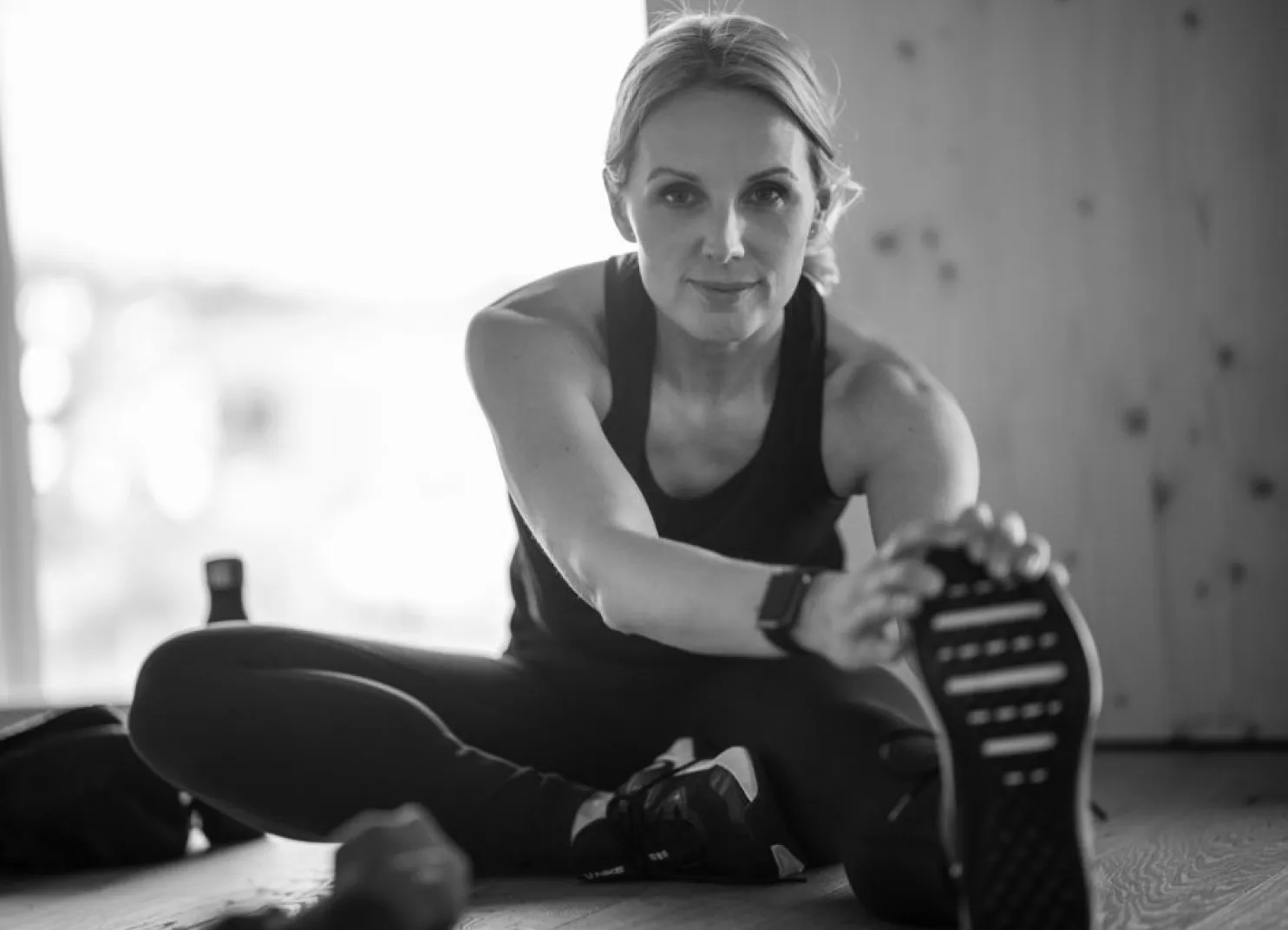 Sportliche Frau sitzt auf dem Boden und schaut in die Kamera