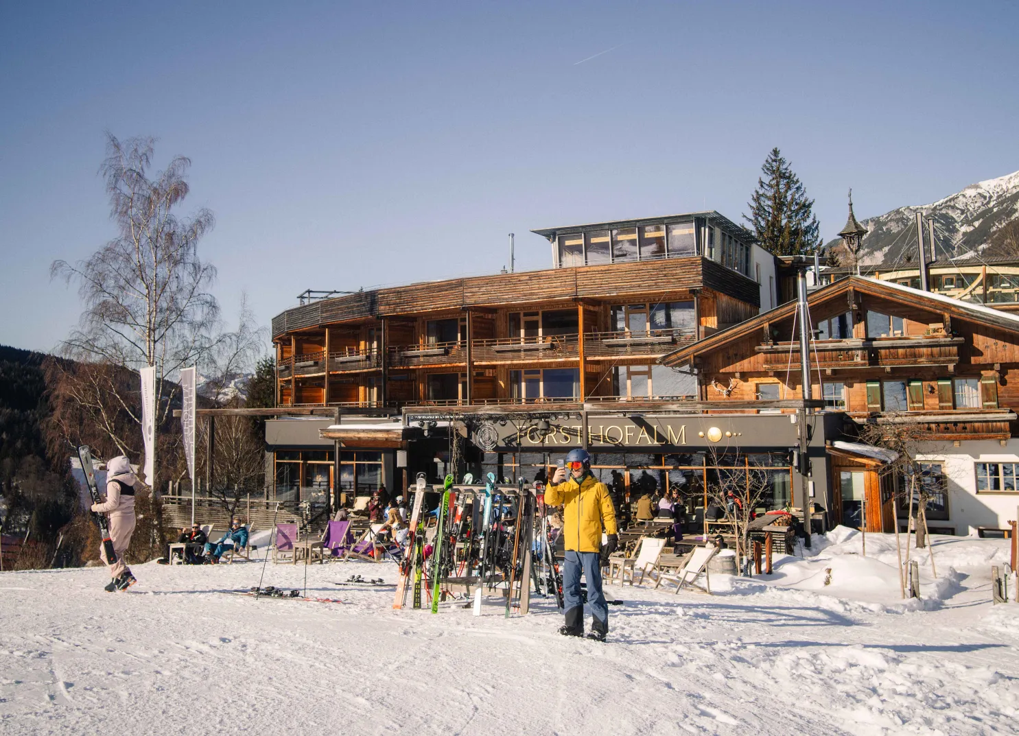 Winterliche Hotelansicht mit Skiern und Personen im Schnee