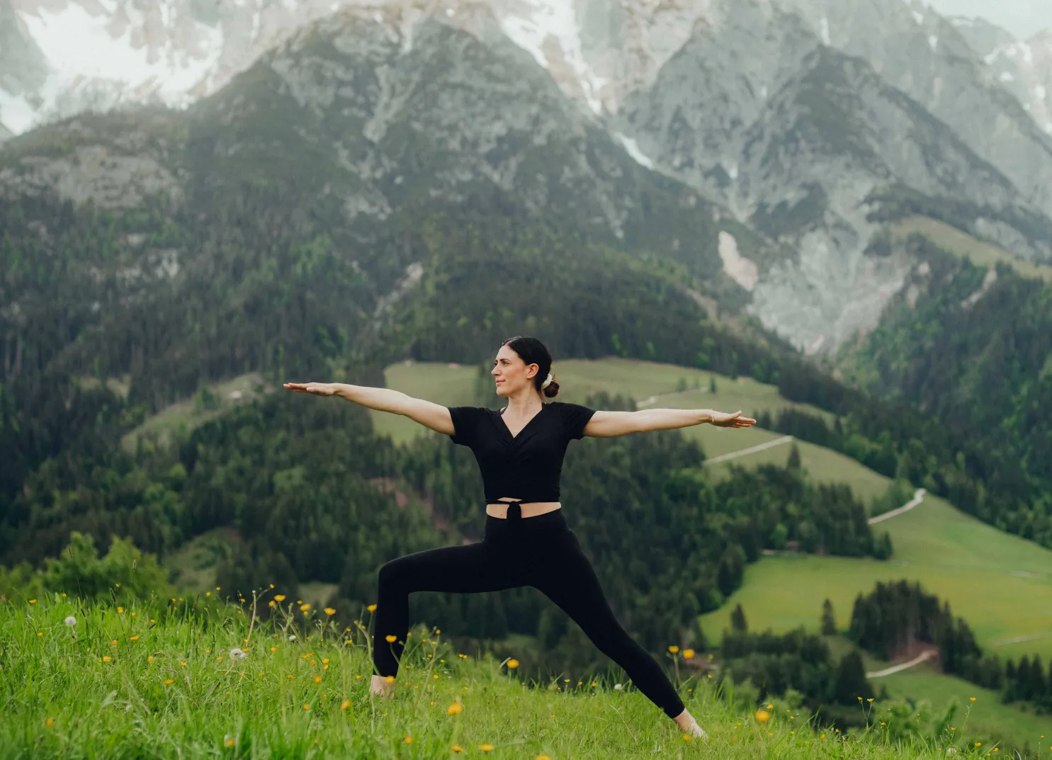 Frau in Yoga-Pose mit Bergen im Hintergrund