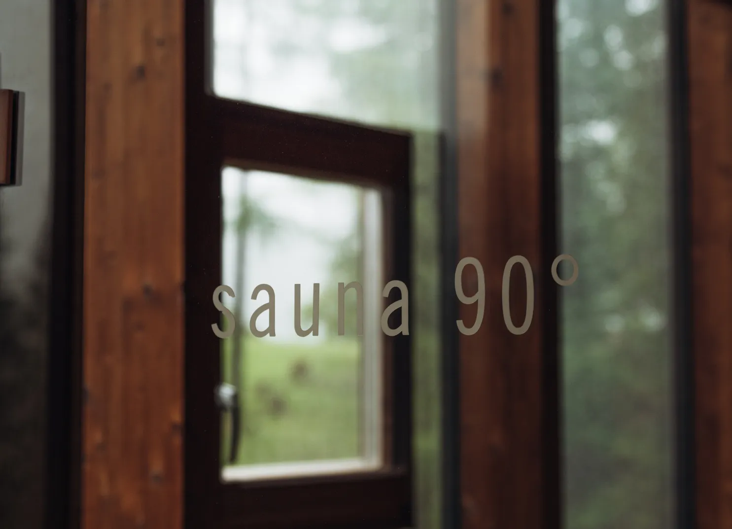 Wooden door with a window and the text 'sauna 90°'