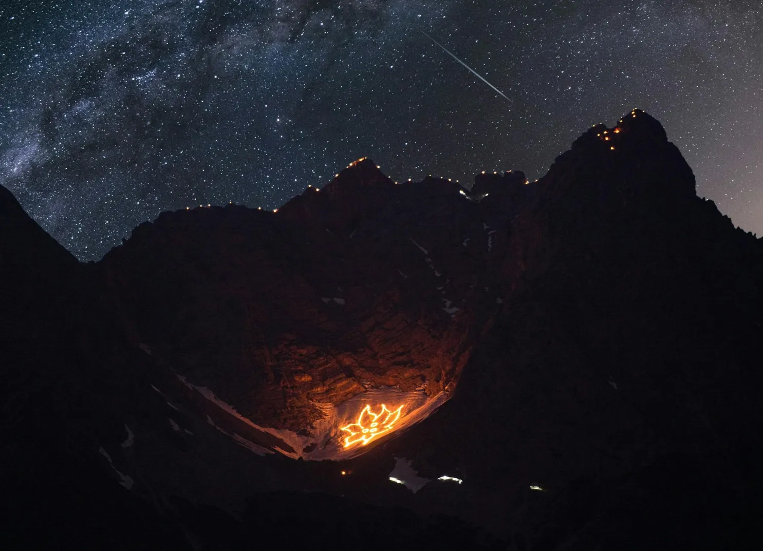Glowing fire on a mountain under a starry sky