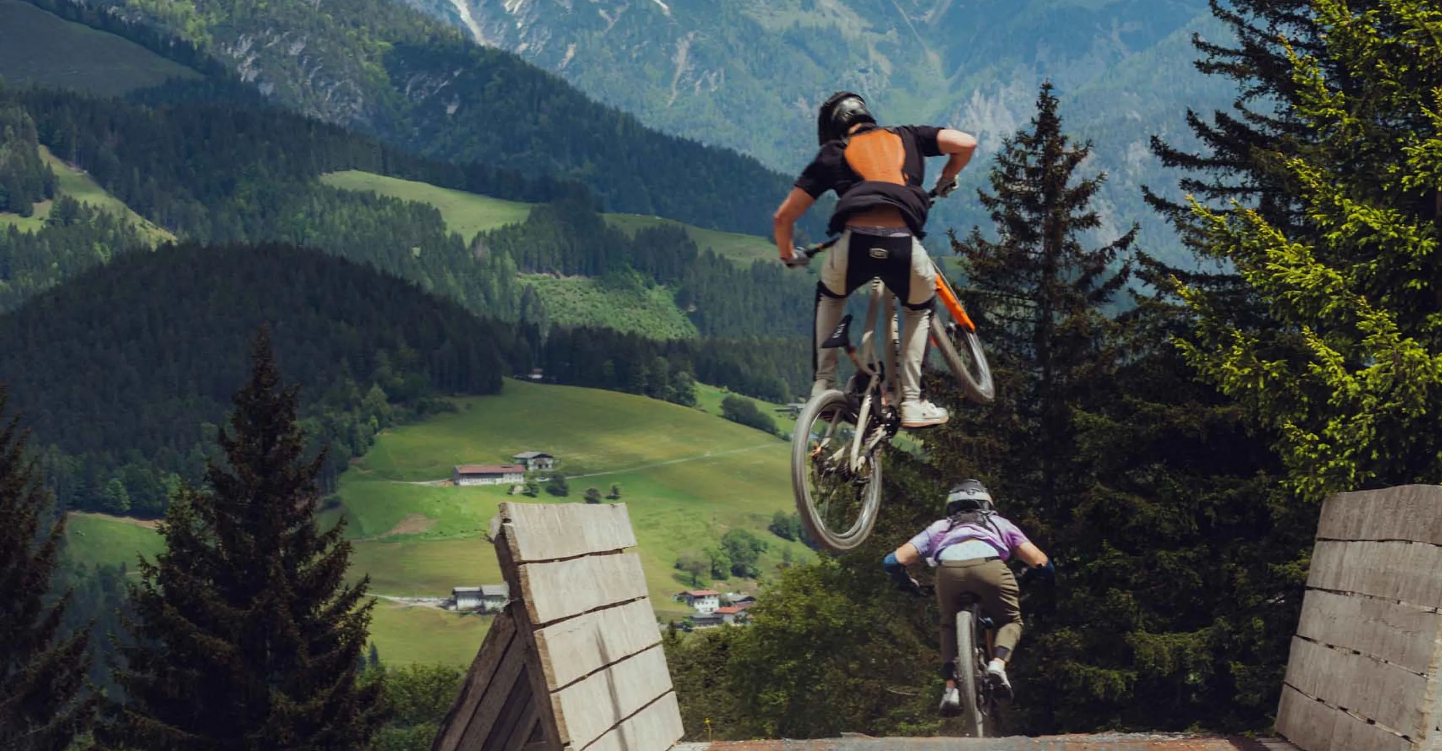 Biker jumps over a wooden ramp in the mountains