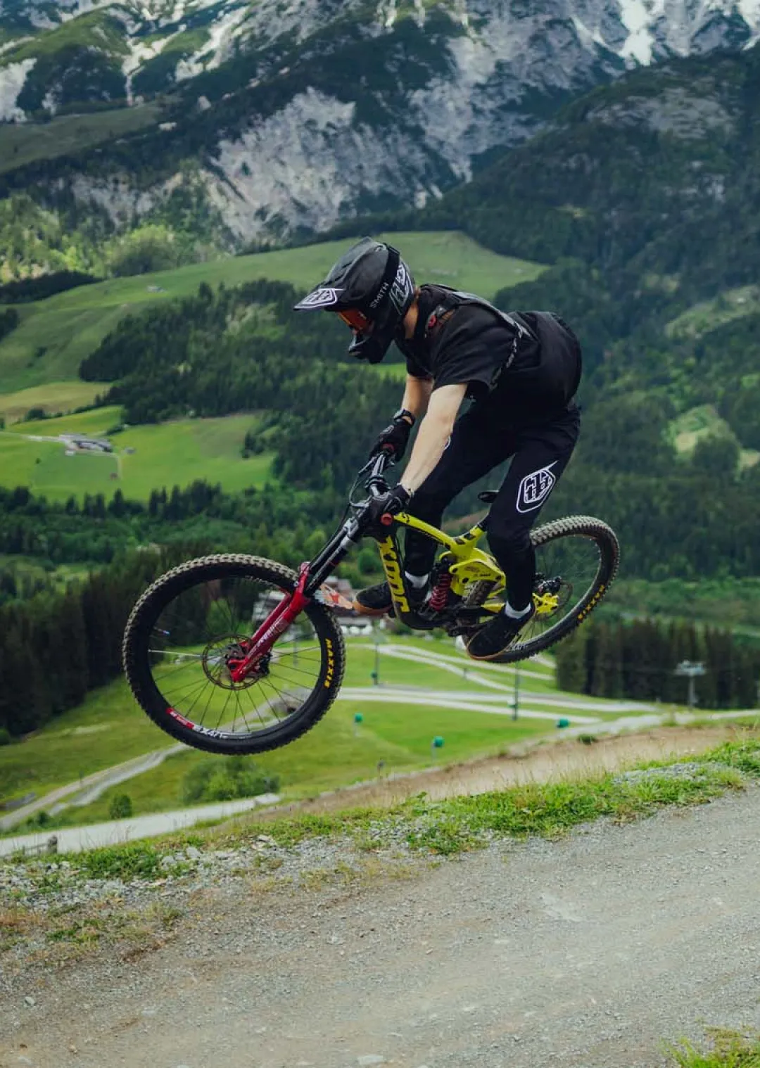 Mountainbiker springt auf einem Trail in den Alpen.