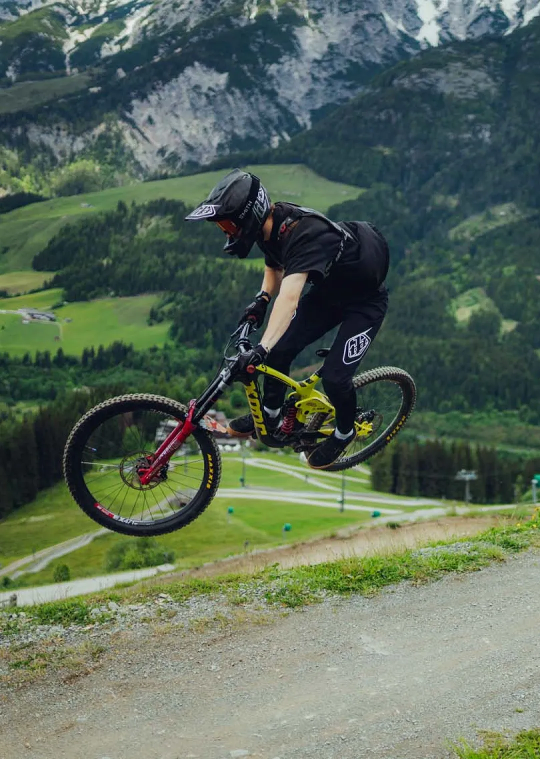 Mountain biker jumping over a slope with mountains in background