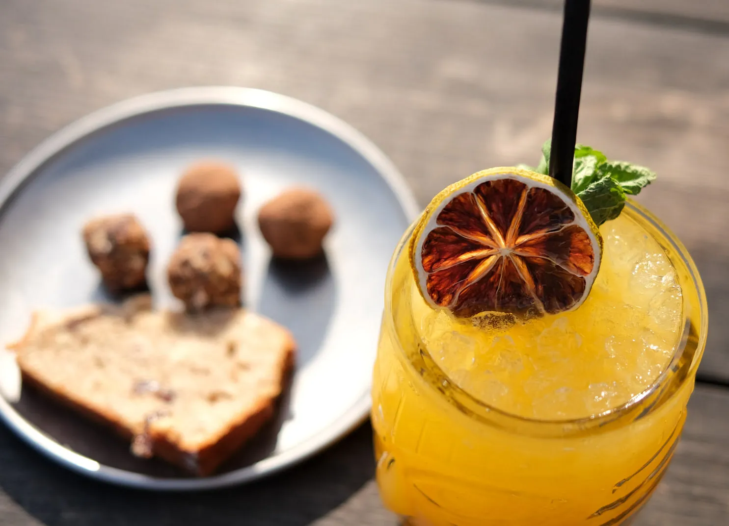 Cocktail with dried fruit and mint, dessert in background