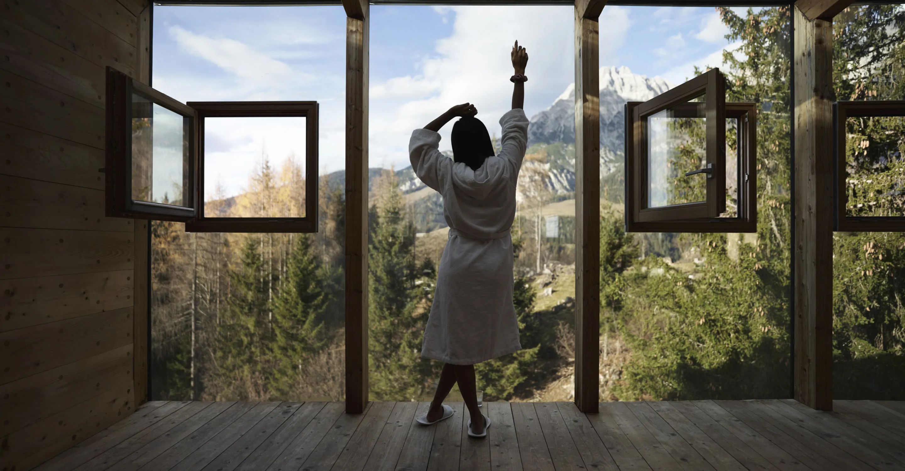 Person in einem Bademantel mit Ausblick auf die Berge