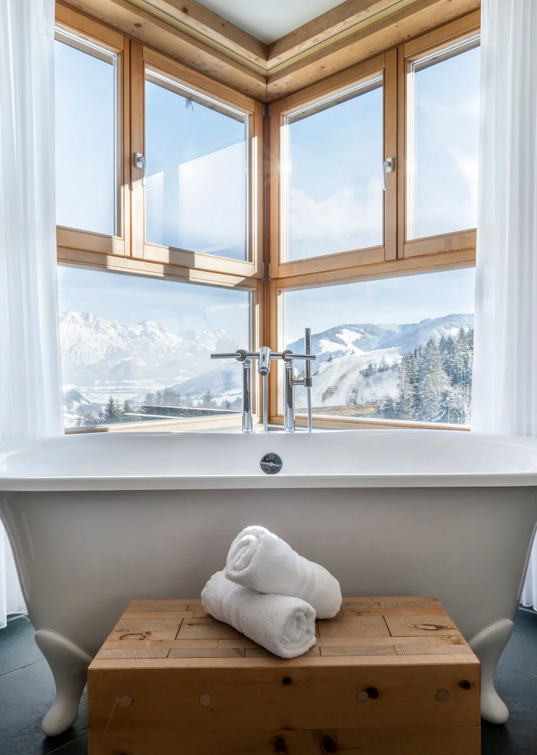 Badewanne mit Blick auf die Berge und Fenster aus Holz