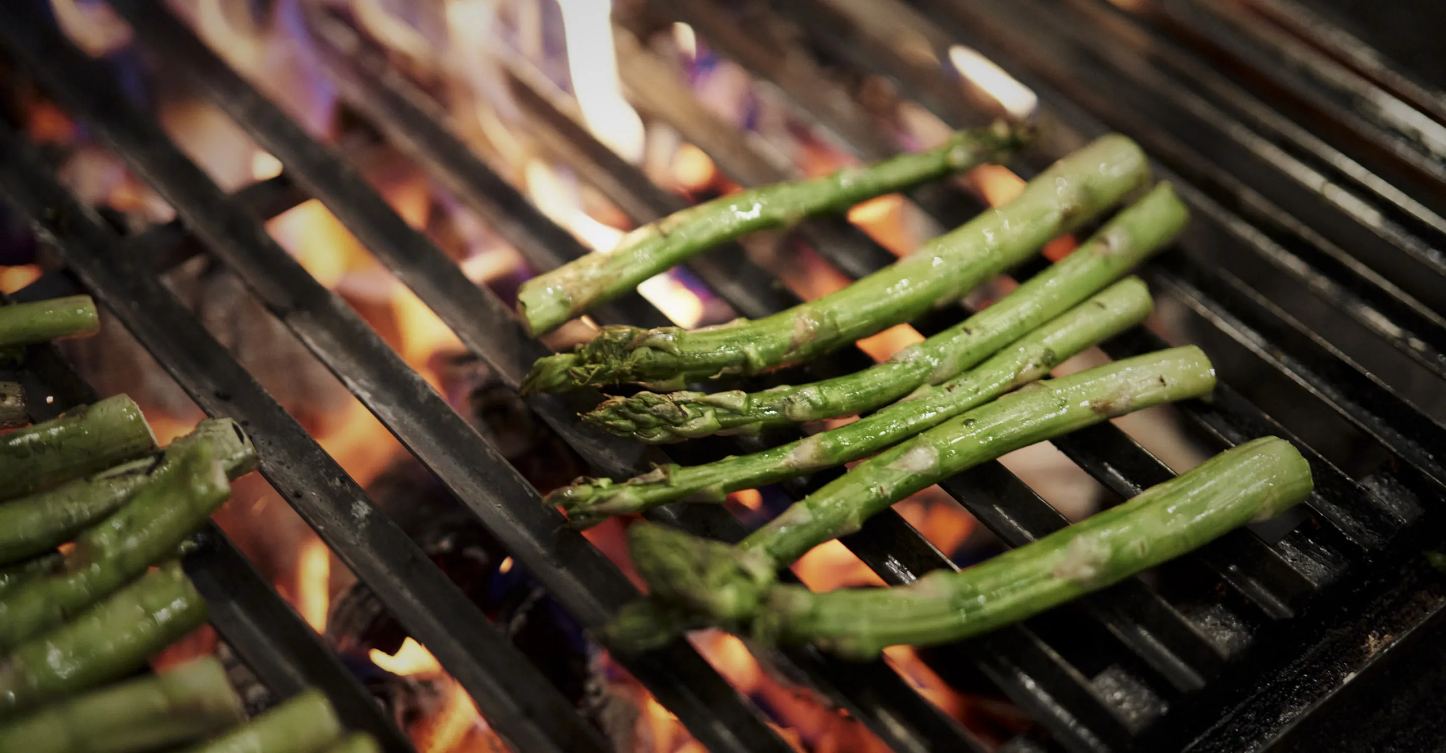 Grilled asparagus on a grill with flames